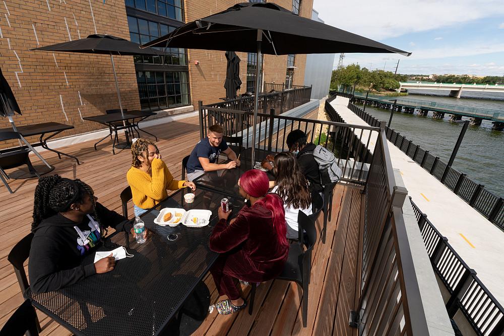 有滨水景观的桌子. 学生们在建筑的屋顶上享受着充足的聚会空间...