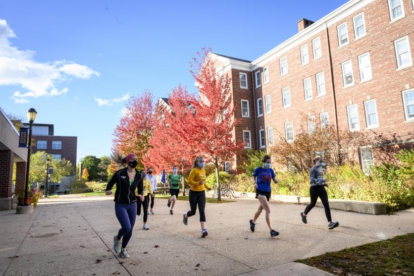 女子田径队在秋天跑在伍德大厅后面.